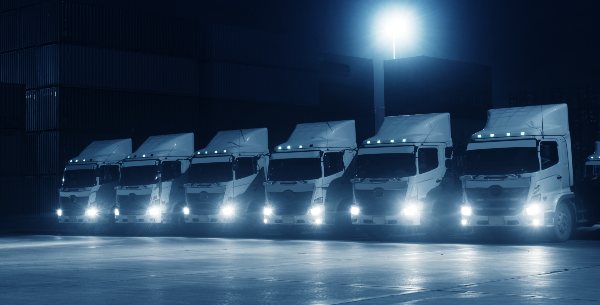 6 delivery trucks have their headlights on for night time driving 
