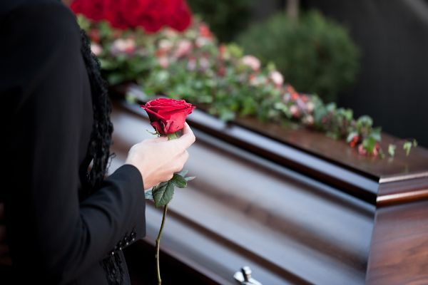 A woman holds a red rose as she says good buy to a loved one in a Colorado cemetery 