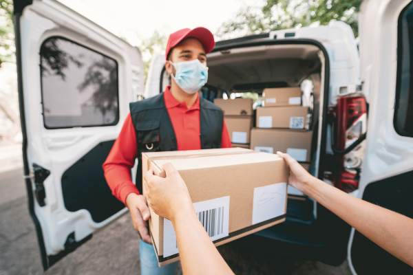 Delivery driver wearing a mask delivers a package